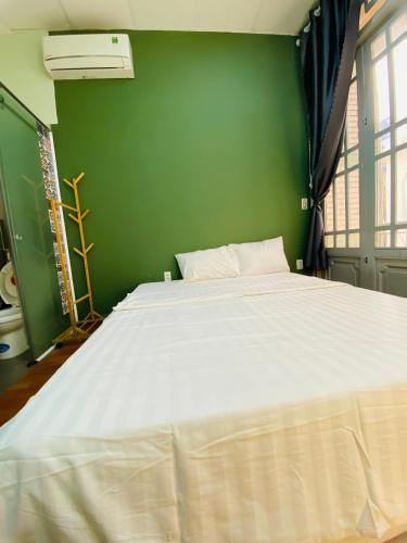 - une chambre avec un grand lit blanc dans un mur vert dans l'établissement Tokyo Homestay, à Hô-Chi-Minh-Ville