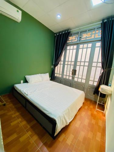 - une chambre avec un grand lit dans un mur vert dans l'établissement Tokyo Homestay, à Hô-Chi-Minh-Ville