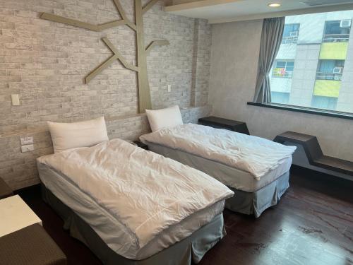 two beds in a room with a brick wall at Kaili Hot Spring Hotel in Jiaoxi