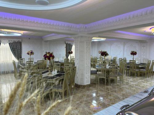 ein Esszimmer mit Tischen, Stühlen und lila Beleuchtung in der Unterkunft Zilol Baxt Hotel in Samarkand