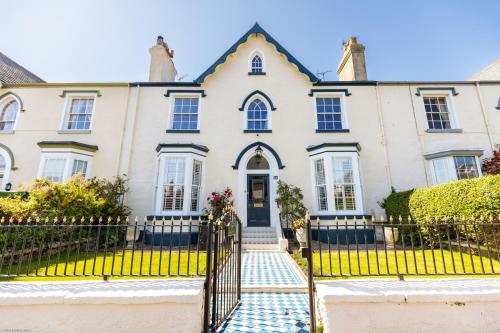 a large white house with a black gate at Abbey Lodge, Llandudno - Period Townhouse, 5 bedrooms & bathrooms, with Hot Tub & Private Parking in Llandudno