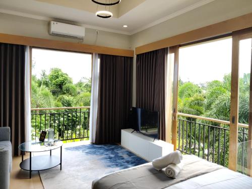 een slaapkamer met een balkon, een bed en een televisie bij SUNNYRENT. Guest villa Dreamland in Ungasan