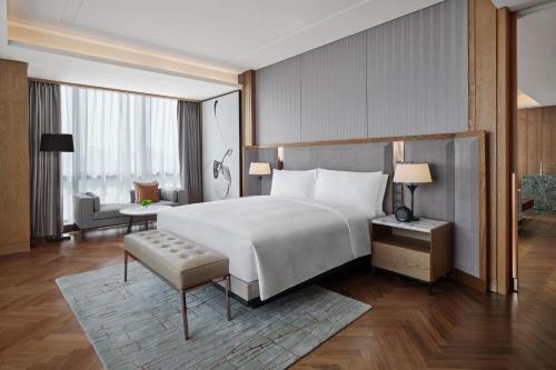 a bedroom with a large bed and a living room at JW Marriott Hotel Taiyuan in Taiyuan