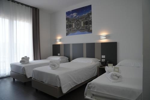 a hotel room with three beds with white sheets at HOTEL MOSAICO in Matera