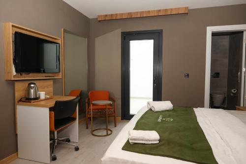 a bedroom with a bed and a desk and a tv at Gardenmode Airport Hotel in Taşoluk