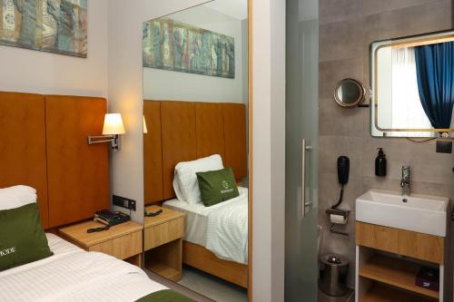 a bedroom with a bed and a sink and a mirror at Gardenmode Airport Hotel in Taşoluk