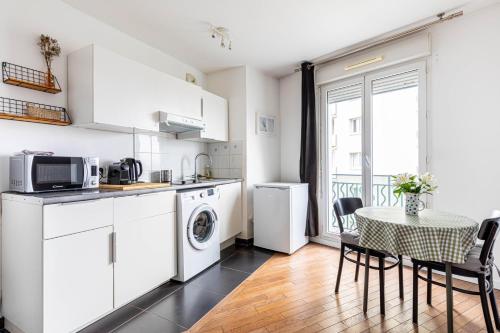 une cuisine avec des appareils blancs et une table avec des chaises dans l'établissement GuestReady - Studio confortable à Romainville, à Romainville