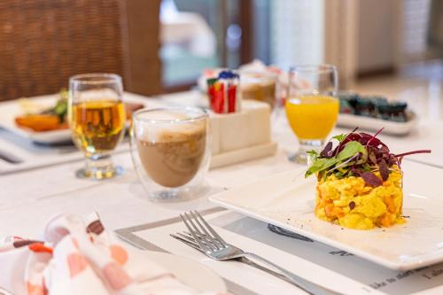 Una mesa con un plato de comida y vasos de bebidas. en Hyde Park Guest House, en Johannesburgo