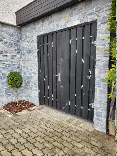 a black garage door with a tree in front of it at Einzigartige Traumwohnung mit Whirlpool & Sauna bietet Luxus und Erholung in Neuheilenbach