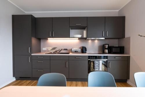 a kitchen with black cabinets and a table and chairs at Moderne & Familienfreundliche Ferienwohnung am Goitzschesee in Pouch