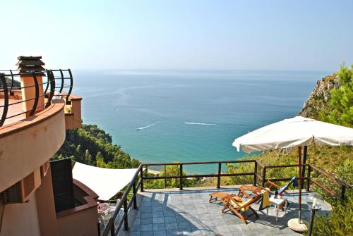 a balcony with chairs and an umbrella and the ocean at VILLA ROMANTIC COVE vista mozzafiato sul mare in Latina