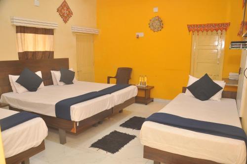 Duas camas num quarto com paredes amarelas em Chitrakut Bungalows em Dwarka