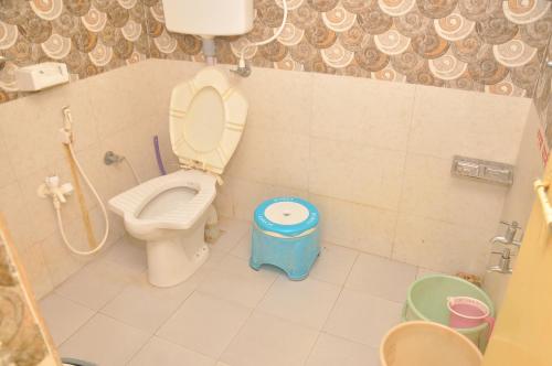 a bathroom with a toilet and a stool in it at Chitrakut Bungalows in Dwarka