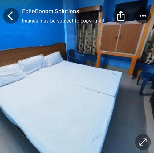 1 dormitorio con 1 cama con sábanas blancas en Ganesh Lodge en Tirupati