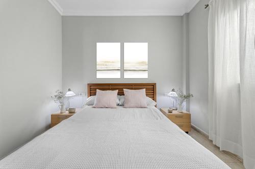 - une chambre blanche avec un grand lit blanc et deux lampes dans l'établissement Piso Don Eduardo, à Arrecife