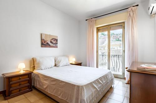 1 dormitorio con cama blanca y ventana en A Look of Taormina Apartments - a Few Steps from the Center en Taormina