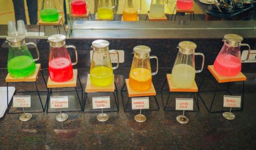 a display of different colored liquids in glass bottles at HOTEL EVERLAND in Rajkot