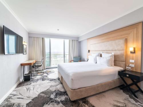 シドニーにあるNovotel Sydney Brighton Beachの大きなベッドと窓が備わるホテルルームです。