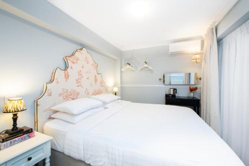 a white bedroom with a large bed and a window at Americana Hotel in London