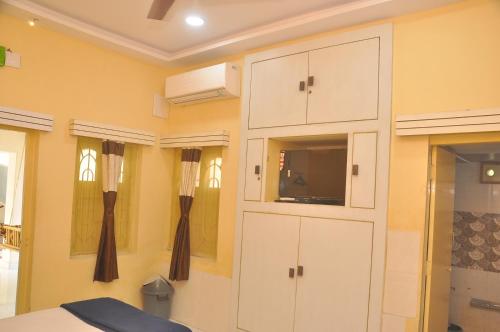a room with white cabinets and a tv on a wall at Chitrakut Bungalows in Dwarka