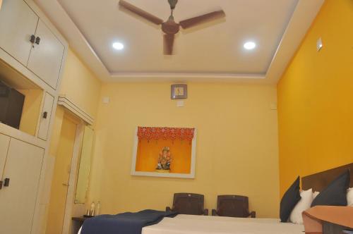 a bedroom with yellow walls and a ceiling fan at Chitrakut Bungalows in Dwarka