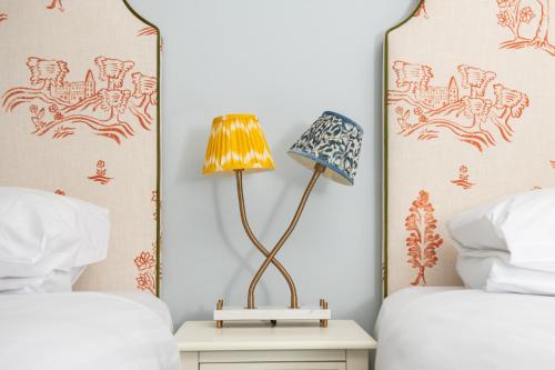 a bedroom with two beds and a lamp on a night stand at Americana Hotel in London
