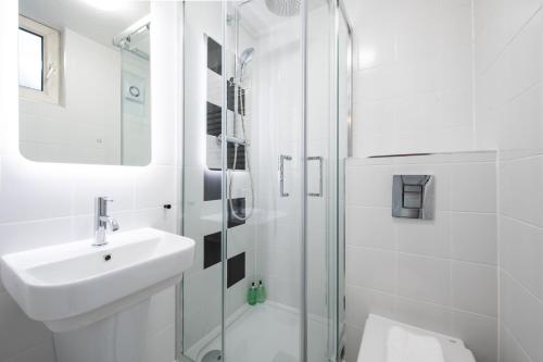 a white bathroom with a sink and a shower at Americana Hotel in London