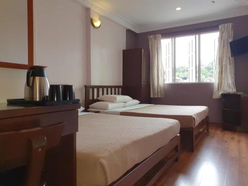 um quarto de hotel com duas camas e uma janela em Hotel Sentosa em Brinchang