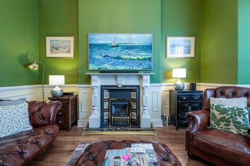 a living room with a fireplace with a tv above it at Abbey Lodge, Llandudno - Period Townhouse, 5 bedrooms & bathrooms, with Hot Tub & Private Parking in Llandudno