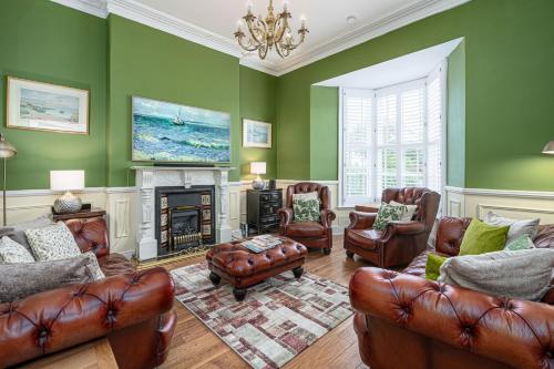 a living room with leather furniture and green walls at Abbey Lodge, Llandudno - Period Townhouse, 5 bedrooms & bathrooms, with Hot Tub & Private Parking in Llandudno