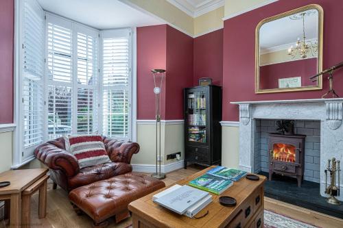 a living room with a couch and a fireplace at Abbey Lodge, Llandudno - Period Townhouse, 5 bedrooms & bathrooms, with Hot Tub & Private Parking in Llandudno