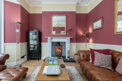 a living room with a couch and a fireplace at Abbey Lodge, Llandudno - Period Townhouse, 5 bedrooms & bathrooms, with Hot Tub & Private Parking in Llandudno