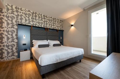 a bedroom with a large bed and a large window at Hotel Sporting Riccione in Riccione