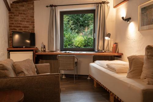 a room with a bed and a desk and a window at Hotel Land Gut Höhne in Mettmann