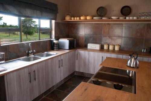 eine Küche mit Holzschränken, einer Spüle und einem Tisch in der Unterkunft Casa de la Presa 3 in Polokwane