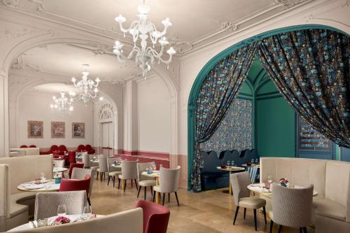 una sala da pranzo con tavoli, sedie e lampadario a braccio di Anglo American Hotel Florence, Curio Collection By Hilton a Firenze