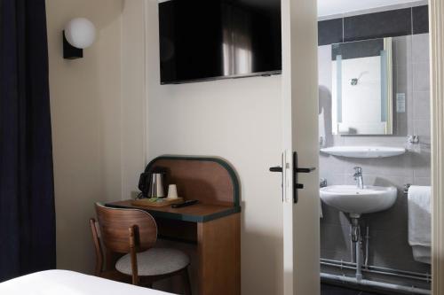 a bathroom with a sink and a mirror and a chair at Bijou Hôtel Paris Boulogne in Boulogne-Billancourt