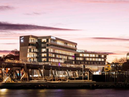 a building with a bridge in front of a river at Novotel Devonport in Devonport