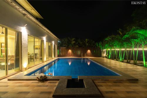 a swimming pool in the middle of a house at night at EKOSTAY - Casa Royale Villa in Alibaug