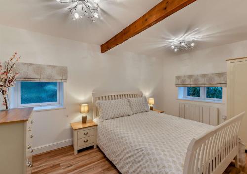 a bedroom with a white bed and two windows at Honey Hirst in Shotley Bridge