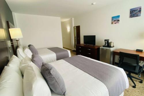 a hotel room with two beds and a desk at La Quinta by Wyndham Reynosa in Reynosa