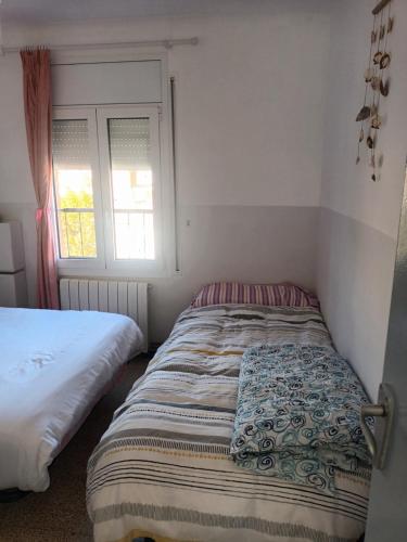 ein kleines Schlafzimmer mit einem Bett und einem Fenster in der Unterkunft Habitacion acogedora en Portbou in Portbou