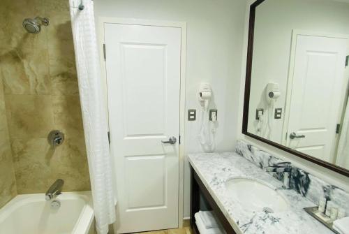 een badkamer met een bad, een wastafel en een spiegel bij La Quinta by Wyndham Reynosa in Reynosa