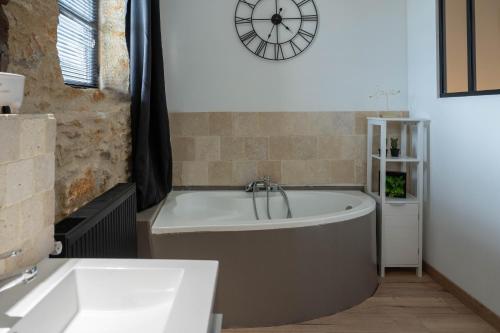 a bath tub in a bathroom with a clock on the wall at Le Havre de Paix en Périgord in La Cassagne
