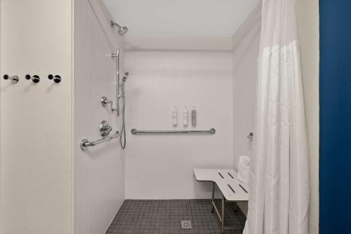 a bathroom with a shower with a bench and a shower curtain at Spark By Hilton Tifton in Tifton