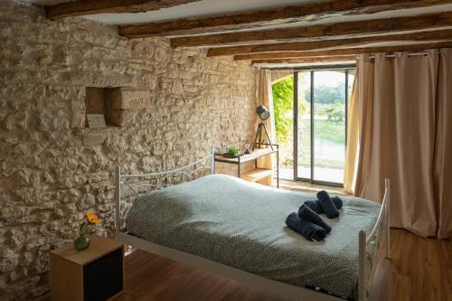 a bedroom with a bed and a stone wall at Le Havre de Paix en Périgord in La Cassagne