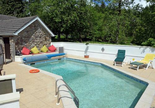 a swimming pool with two chairs and a couch next to it at Sparrows Nest Holiday Cottage in Amroth