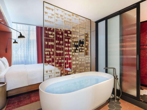 a bath tub in a room with a bedroom at Pullman Budapest in Budapest