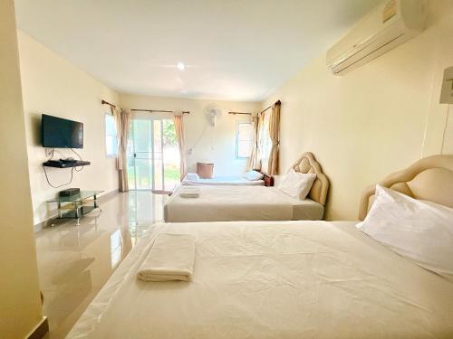 um quarto de hotel com duas camas e uma televisão em พายเนอรี รีสอร์ท @แหล่มแท่น (Pinery Resort) 