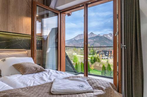 a bedroom with a bed and a large window at Apartamenty Krokusowa Dolina in Kościelisko